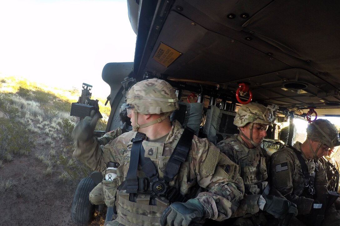 Soldiers wait to take off inside a UH-60 Black Hawk helicopter.