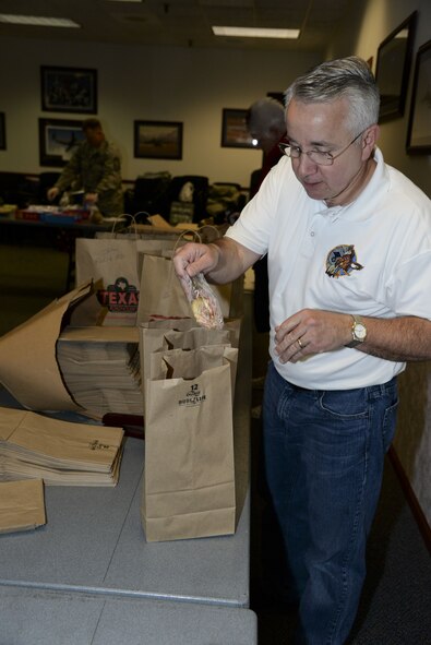 Dean Reed, Dover Chiefs’ Group vice president, adds a holiday card to a bag of cookies Dec. 18, 2017, during Operation Cookie Drop at the 9th Airlift Squadron on Dover Air Force Base, Del. The cookies, holiday cards and handmade gifts were all donated from the community members to ensure each dorm resident received some holiday cheer. (U.S. Air Force photo by Staff Sgt. Aaron J. Jenne)