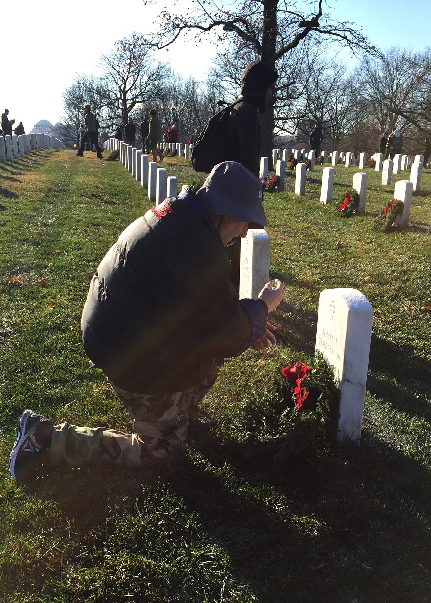 Donald Adriance, veteran and member of the 436th Medical Group at Dover Air Force Base, Del., kneels before the gravesite of a fallen hero Dec. 16, 2017, at Arlington National Cemetery in Arlington, Va. Adriance was one of tens of thousands who volunteered to help place remembrance wreaths at headstones in the national cemetery in support of Wreaths Across America. (U.S. Air Force photo by 2nd Lt. Natasha O. Mosquera)