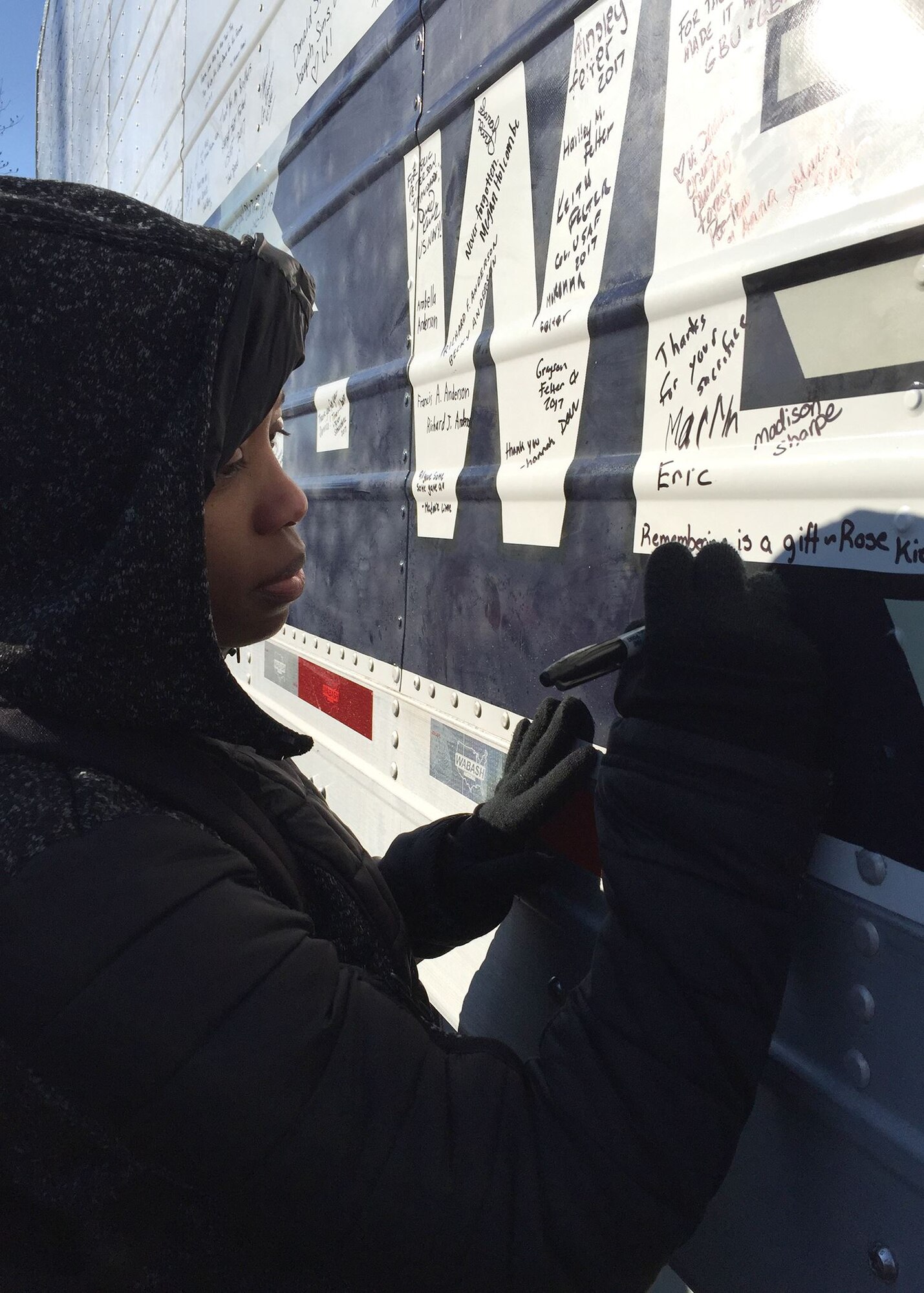 SrA Chelica Thompson, 436th Airlift Wing judge advocate general from Dover Air Force Base, Del., writes a message on one of the wreath-carrying trucks Dec. 16, 2017, at Arlington National Cemetery in Arlington, Va. Through personalized messages, volunteers expressed their gratitude for the fallen for all to see. (U.S. Air Force photo by 2nd Lt. Natasha O. Mosquera)