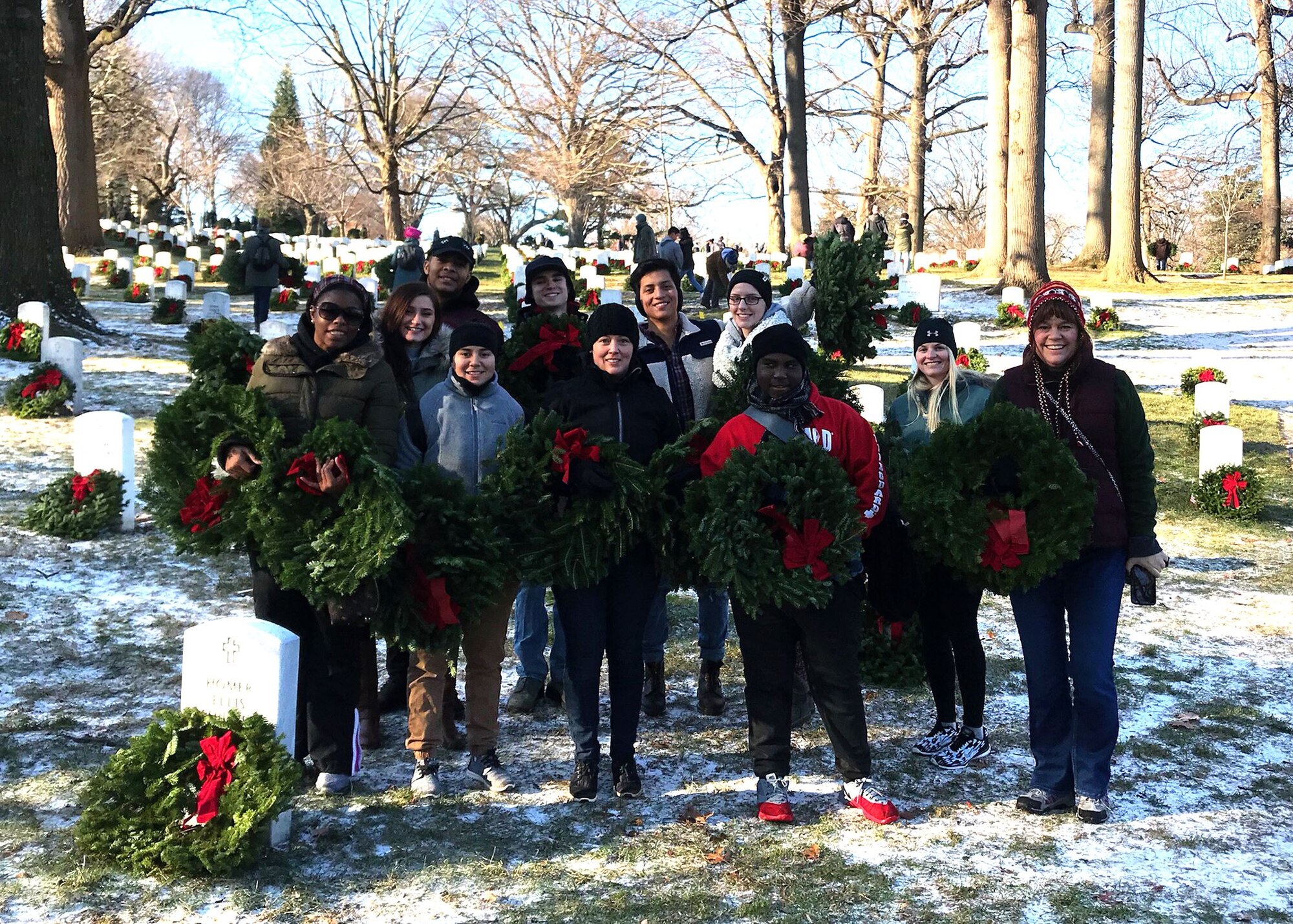 Airmen from the 436th Medical Group at Dover Air Force Base, Del., stand on the grounds of Arlington National Cemetery in Arlington, Va., on Dec. 16, 2017, with their remembrance wreaths in hand. The Airmen were among the thousands of volunteers who helped accomplish Wreaths Across America’s mission to “Remember, Honor, and Teach.” (Courtesy photo)