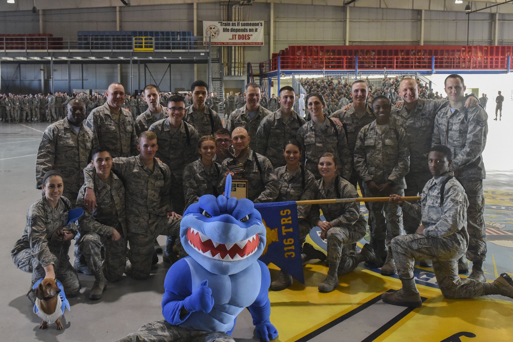 The 316th Training Squadron drill team poses with their trophy after winning each of the categories during the 17th Training Group drill competition at the Louis F. Garland Department of Defense Fire Academy on Goodfellow Air Force Base, Texas, Dec. 15, 2017. Leadership joined in the group photo along with the 316th TRS mascot and Gary the Dachshund. (U.S. Air Force Photo by Airman 1st Class Zachary Chapman/Released)