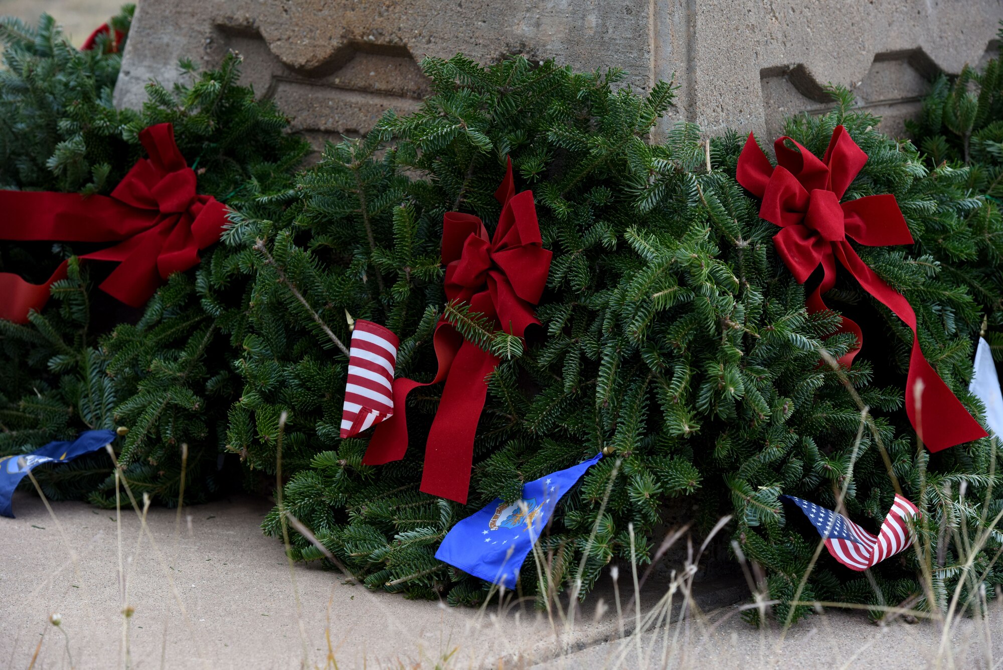 Symbolic wreaths are laid at the base of the flag in Belvedere Memorial Park, San Angelo, Texas, Dec. 16, 2017. One wreath per branch and a POW/MIA wreath was laid at the base of the flagpole during the Wreaths Across America Ceremony. (U.S. Air Force photo by Airman 1st Class Seraiah Hines/Released)