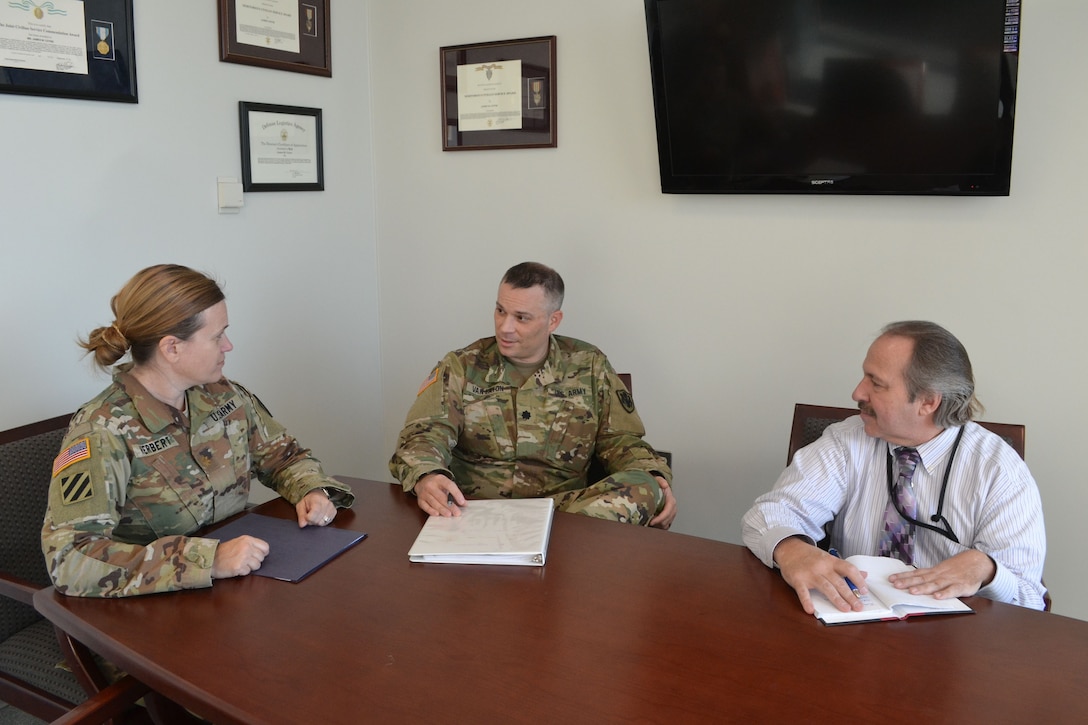 Army Reserve Lt. Col. Josh Van Eaton (center) meets with Army Maj. Heather Herbert (left) and Michael Lunceford (right), an administrative specialist  in the DLA Office of General Counsel. (Photo by Dianne Ryder.)