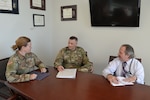 Army Reserve Lt. Col. Josh Van Eaton (center) meets with Army Maj. Heather Herbert (left) and Michael Lunceford (right), an administrative specialist  in the DLA Office of General Counsel. (Photo by Dianne Ryder.)