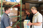 Jonathan Connell, CEO, and Todd Daughtry, COO, co-owners of veteran-owned small business C & C Containers, LLC meet in their Albany, Georgia, warehouse with Georgia PTAC Procurement Counselor Bridget Bennett to discuss product packaging and marking requirements for shipment of medical supplies.