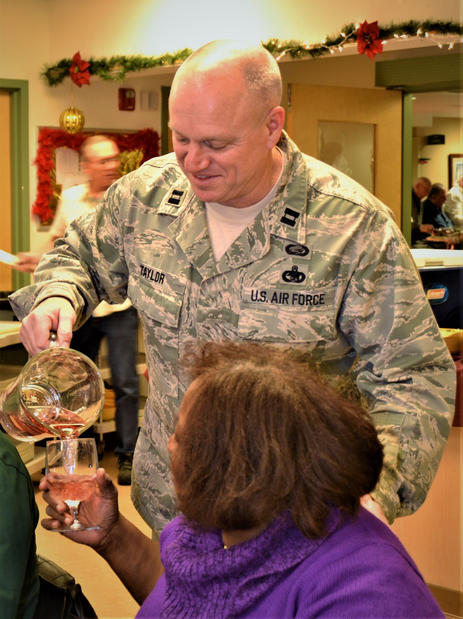 Capt. Dan Taylor, 111th Logistics Readiness Squadron logistics officer out of Horsham Air Guard Station, Pa., volunteers at the Delaware Valley Veterans Home, Philadelphia, by pouring drinks for the residents and their families during a Pa. National Guard visit Dec. 14, 2017. An annual event, the service members shared conversation and a meal with approximately 170 veterans and their families. (U.S. Air National Guard photo by Tech. Sgt. Andria Allmond)