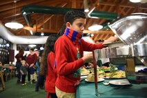The son of a deployed family member reaches for food after taking pictures with Santa at J.R. Rockers on Ramstein Air Base, Dec. 15, 2017. The 86 Airlift Wing Airman and Family Readiness Center organizes Deployed Family member events once a month, which are offered to family members of deployed Airmen to increase a sense of community among these families while their loved ones are away.