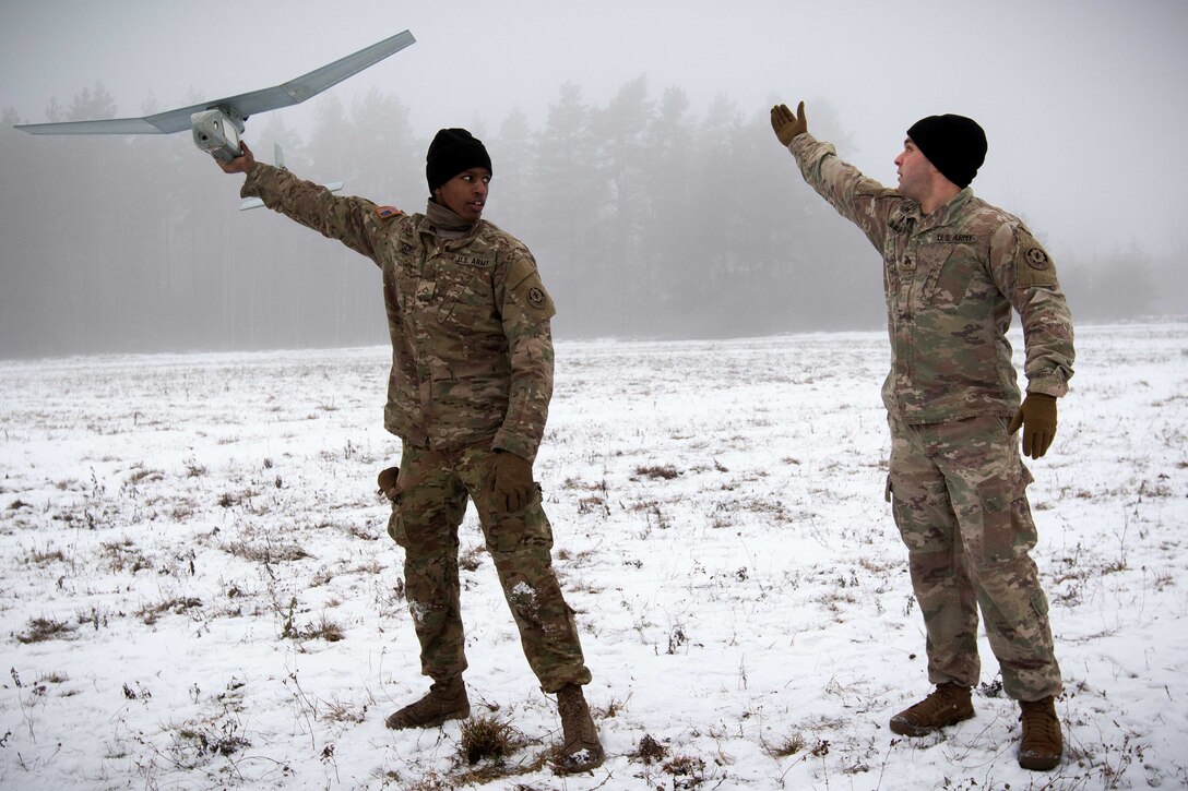 Pfc. Alexander Jones, left, receives instructions from Sgt. Ryan Danielian on how to properly launch a Raven Unmanned Aerial Vehicle