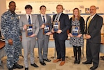 IMAGE: DAHLGREN, Va. (Dec. 11, 2017) - Four members of the Naval Surface Warfare Center Dahlgren Division (NSWCDD) Sly Fox Mission 21 team - Charles Miller, Troy Newhart, Joshua Taylor, and Jessica Hildebrand - hold the Sly Fox Awards they received from NSWCDD Commanding Officer Capt. Godfrey 'Gus' Weekes and NSWCDD Technical Director John Fiore at the command's leadership meeting. They were among seven members of Sly Fox Mission 21 recognized for developing the SCAPEGOAT chemical, biological, and radiological (CBR) detection system. The team demonstrated a new capability to deploy the modular CBR sensor system aboard multiple unmanned aerial vehicle platforms in a demonstration held last June on the Potomac River Test Range. SCAPEGOAT was designed, prototyped, and tested over a six-month period as the team engaged in the command's Sly Fox Program. With its relatively low cost and modular interfaces, the SCAPEGOAT system demonstrates the use of emerging technology in meeting warfighter needs. The Sly Fox program is an NSWCDD Naval Innovative Science and Engineering (section 219) funded rapid prototyping program intended to develop the science and engineering workforce, mostly junior scientists and engineers, while applying their talents to known technology gaps. Like the previous 20 missions - including efforts in directed energy, radar systems, unmanned systems, and cyber threats - Sly Fox Mission 21 took advantage of the diverse skills of its team members to tackle a mission that is important to NSWCDD, its customers, and the warfighters.