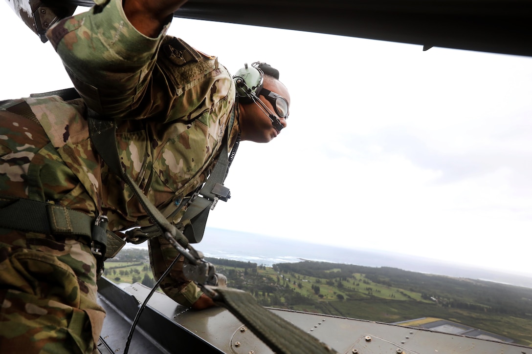 Army Chief Warrant Officer 3 Gregory Benson looks out the back ramp of a CH-47 Chinook helicopter.