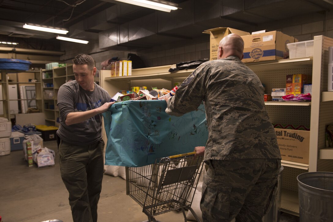 Master Sgt. Lucas Sanders, 366th Fighter Wing first sergeant, and Master Sgt. Phillip Horton, 266th Range Squadron first sergeant, roll in a food donation bin, Dec. 19, 2017, at Mountain Home Air Force Base, Idaho. The children at the Youth Center collected more than 250 food items. (U.S. Air Force photo by Senior Airman Lauren-Taylor Levin)
