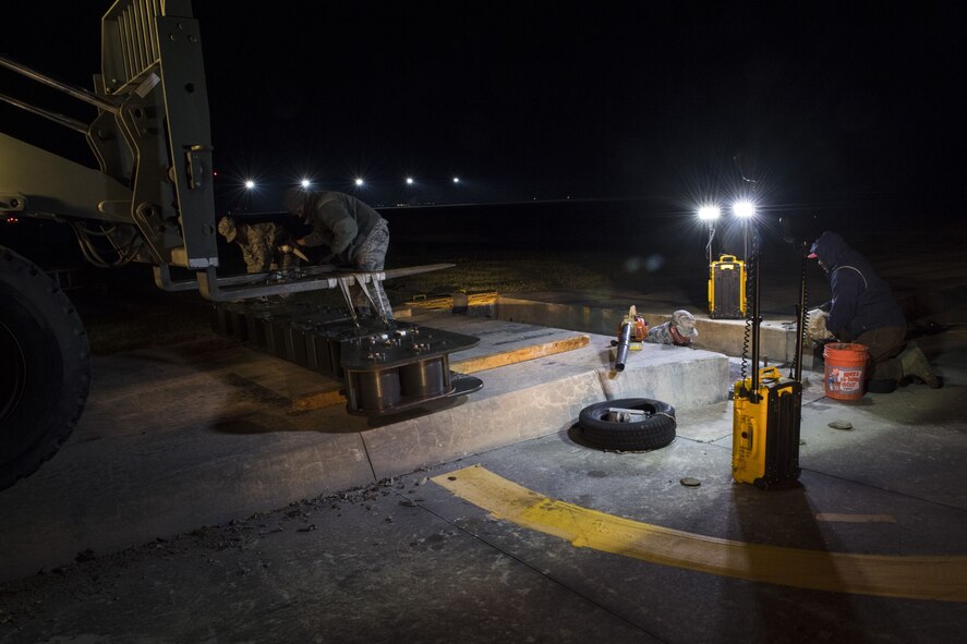 Airmen from 23d Civil Engineer Squadron power production shop, work on various tasks while replacing a fairlead beam, Nov. 15, 2017, at Moody Air Force Base, Ga. The beam is a part of a BAK-12 arresting system that is used on the runway to slow down fighter aircraft in emergency situations. (U.S. Air Force photo by Senior Airman Janiqua P. Robinson)