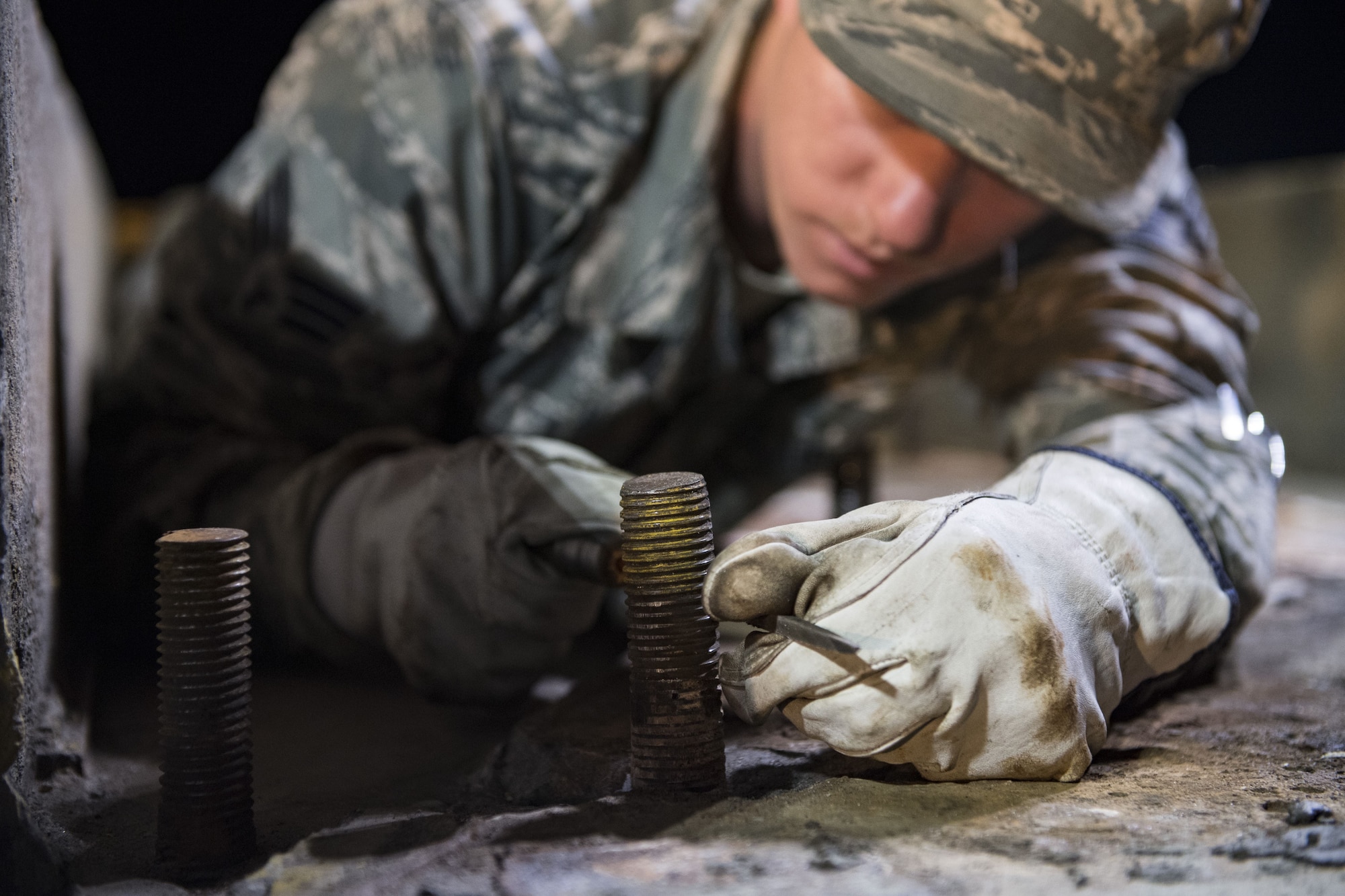 Senior Airman Matthew Melton, 23d Civil Engineer Squadron power production journeyman, clears the threads on a bolt, Nov. 15, 2017, at Moody Air Force Base, Ga. The bolts will hold a fairlead beam in place which is a part of a BAK-12 arresting system that is used on the runway to slow down fighter aircraft in emergency situations. (U.S. Air Force photo by Senior Airman Janiqua P. Robinson)