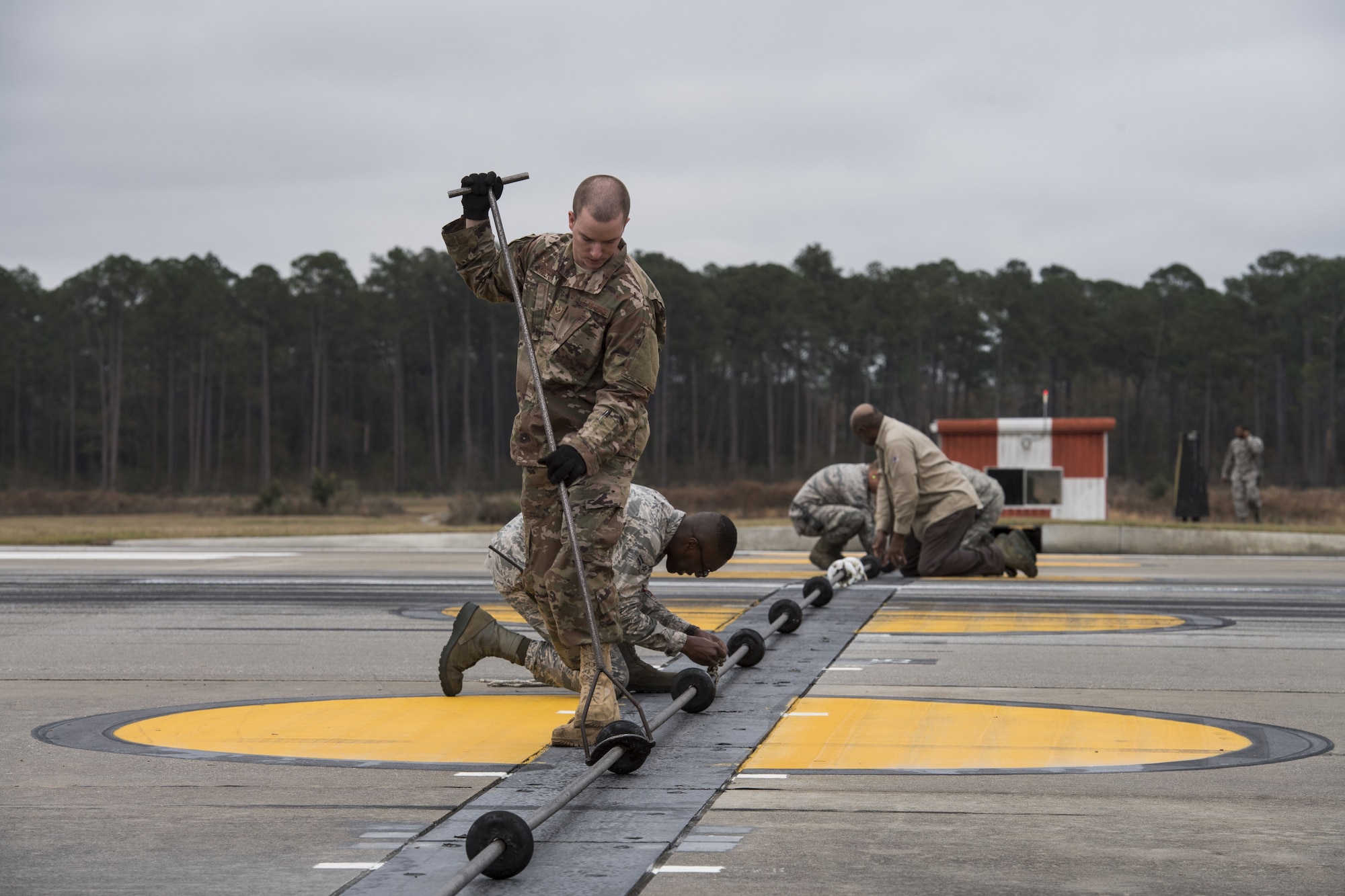 Airmen from 23d Civil Engineer Squadron power production shop, work on various tasks while preparing an arresting system for use, Dec. 19, 2017, at Moody Air Force Base, Ga. The beam is a part of a BAK-12 arresting system that is used on the runway to slow down fighter aircraft in emergency situations. (U.S. Air Force photo by Senior Airman Janiqua P. Robinson)