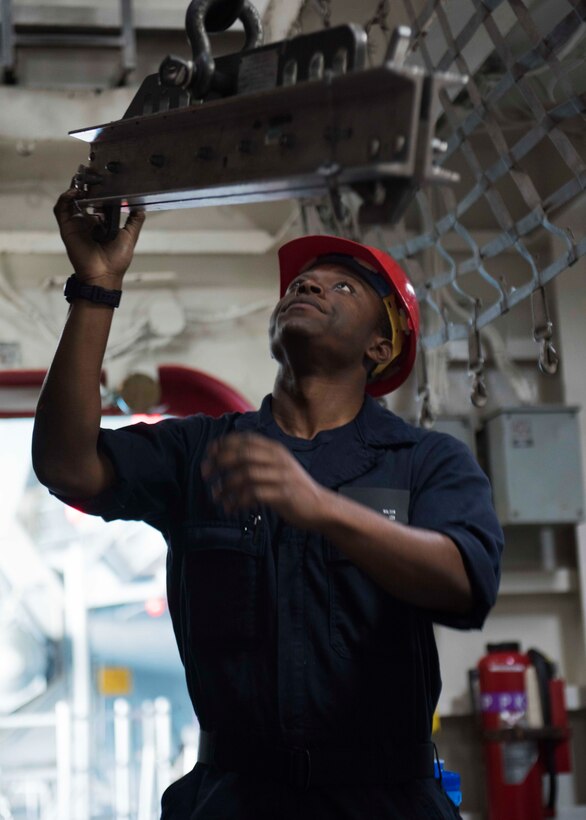 A seaman moves a hoist on the aircraft carrier USS Theodore Roosevelt.