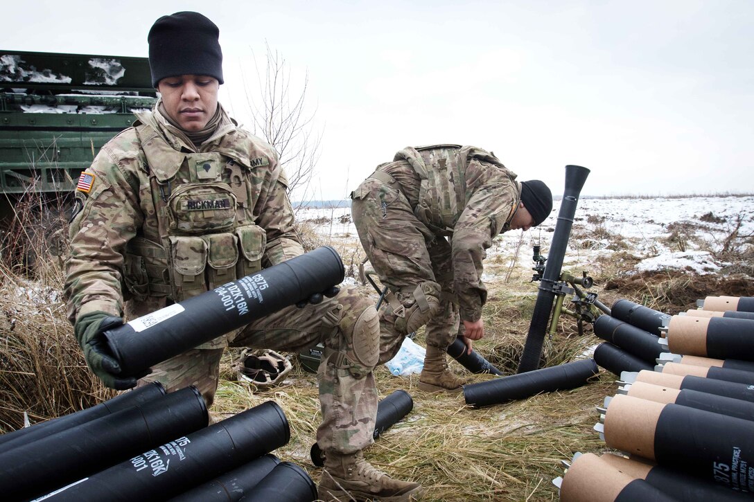 Army Spcs. Deonte Rickman, left, and Jonathan Mendoza prepare ammunition for their team’s 81-millimeter mortar.