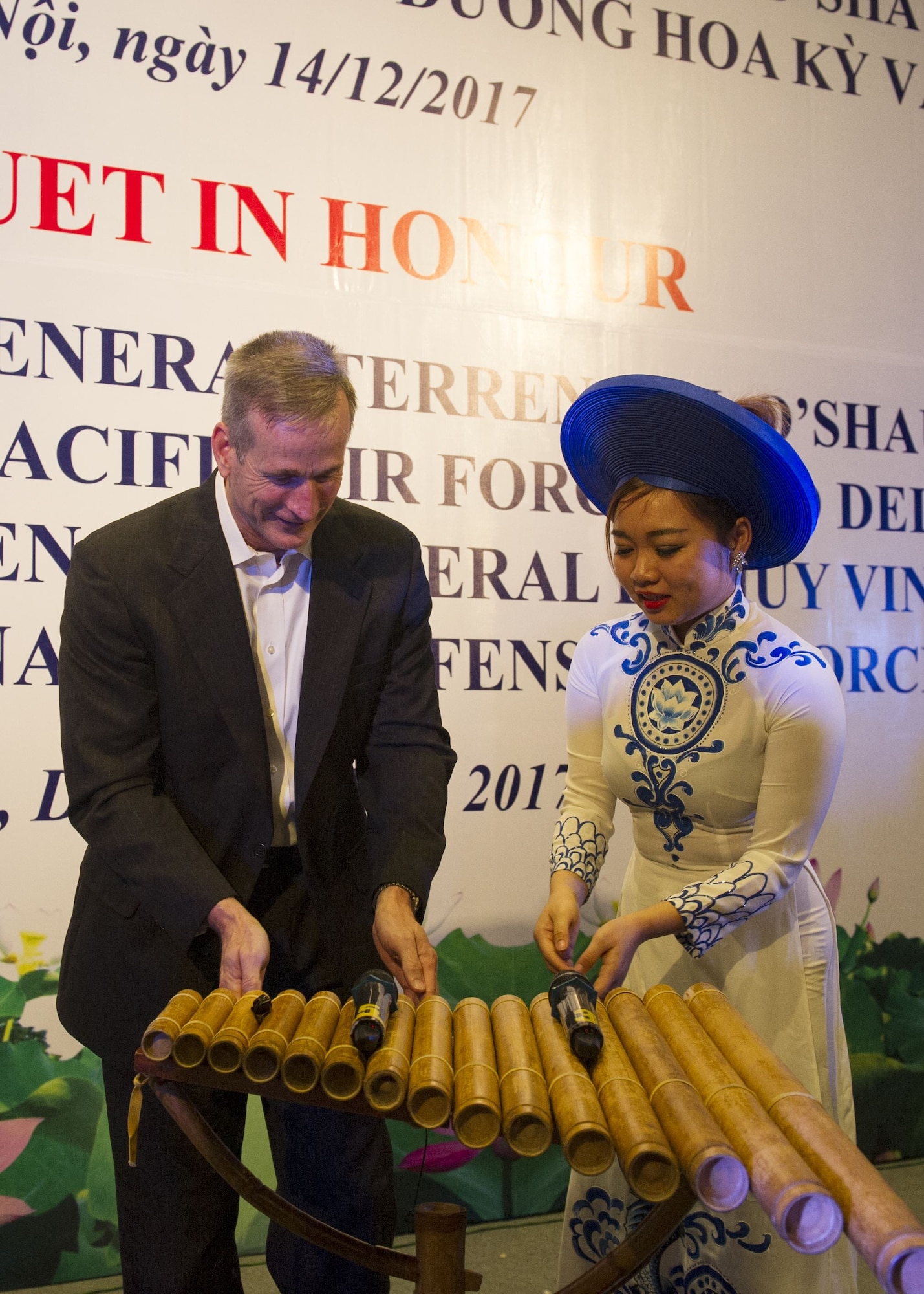 Gen. Terrence J. O’Shaughnessy, Pacific Air Forces commander, is instructed on how to play a traditional instrument by a Vietnamese Air Defense-Air Force (ADAF) musician, during a dinner hosted by the ADAF, Hanoi, Vietnam, Dec. 14