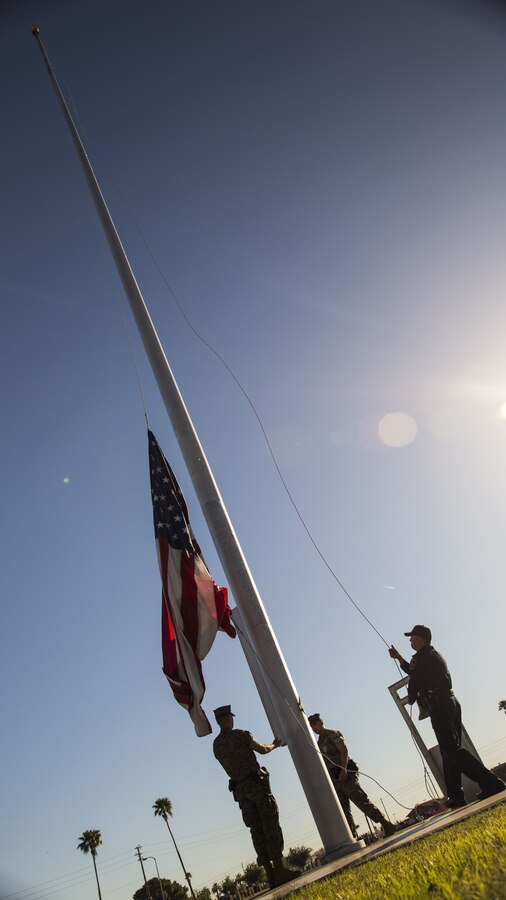 Two military policeman and a civilian provost marshal officer assigned to the Provost Marshal's Office raise the American flag for morning colors during the 5th Annual Sexual Assault Awareness and Response Motorcycle Ride at Marine Corps Air Station Yuma, Ariz., Thursday, April 6, 2017. The motorcycle ride promotes Sexual Assault Awareness Month, raises awareness of the Sexual Assault Prevention and Response (SAPR) Program, and its resources available at MCAS Yuma. The event also supports Amberly’s Place, an organization that provides services to victims and their families. (U.S. Marine Corps photo taken by Lance Cpl. Christian Cachola)