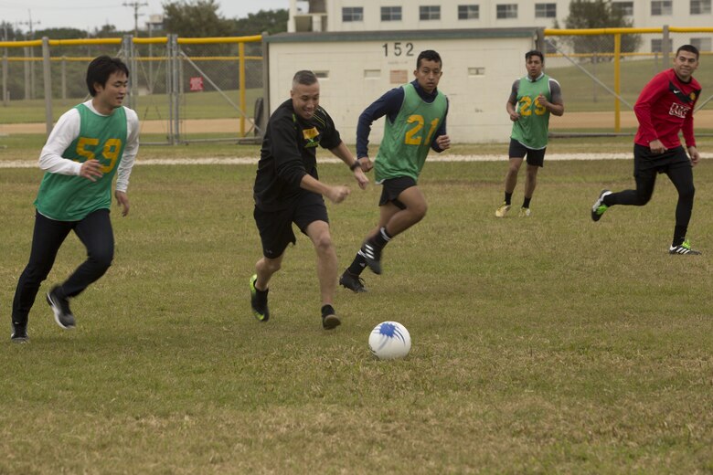 MCAS FUTENMA, OKINAWA, Japan— Chief Petty Officer Michael Garcia races a Kokusai University Student to the ball during a soccer game Dec. 17 on Marine Corps Air Station Futenma, Okinawa, Japan.