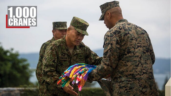 Japan Self-Defense Force, Warrant Officer Katsunori Taira, presents the III Marine Expeditionary Force Sergeant Major, Sgt. Maj. Mario Marquez and Marines with the 9th Engineer Support Battalion with gifts including 1,000 cranes to honor Master Sgt. Hector Trujillo at Camp Courtney, Okinawa, Japan, Dec. 20, 2017. Master Sgt. Trujillo was injured Dec. 1, 2017 on the Okinawa Expressway. In Japanese culture, the crafting of 1,000 paper cranes is known as “senbazuru” and is symbolic for peace and healing. (U.S. Marine Corps photo by Sgt. Ricky Gomez)