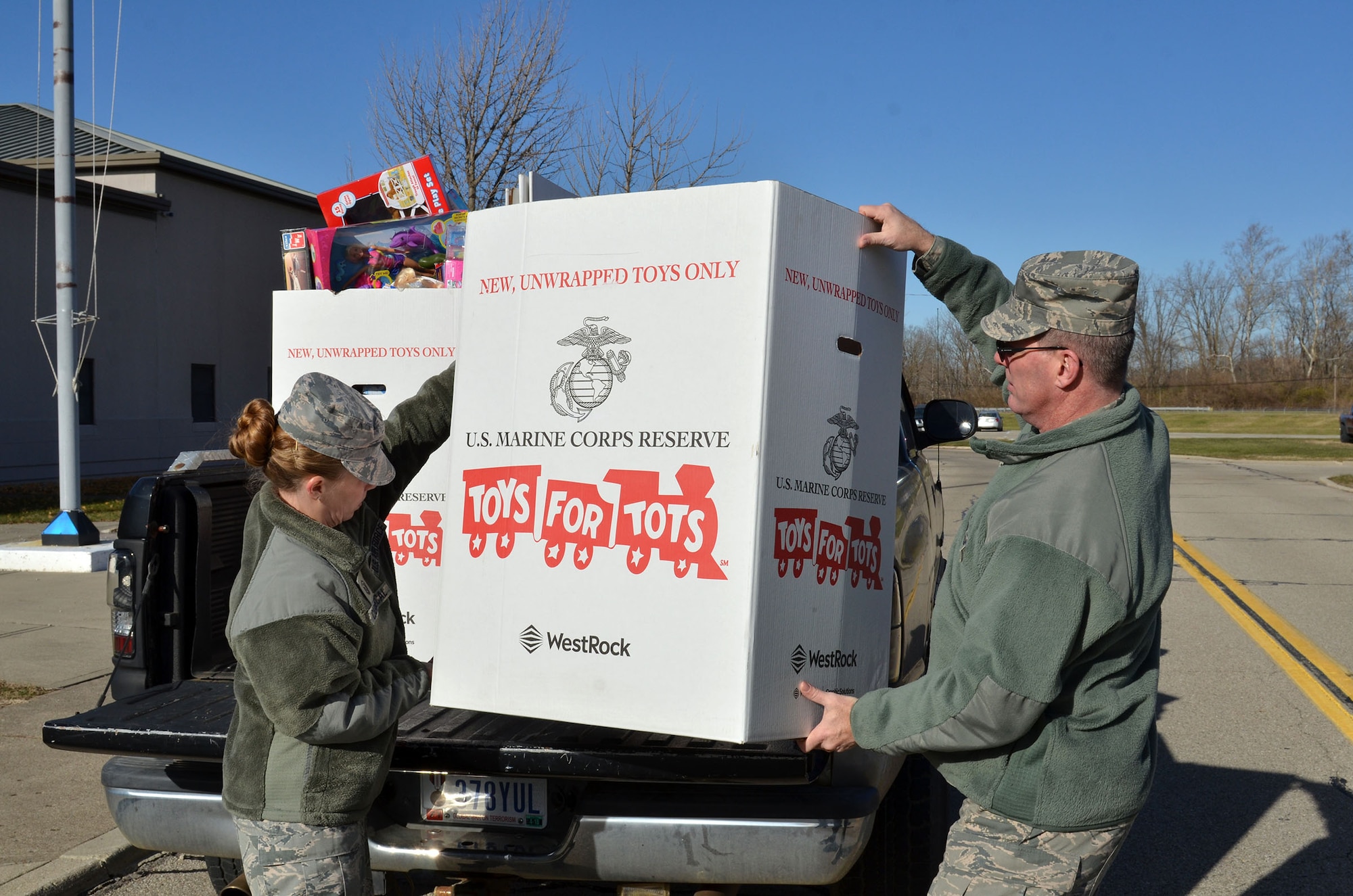 Master Sgts. Sierra A. Cabungcal, left, 445th Operations Support Squadron first sergeant, and Jay L. Swanson, 445th Force Support Squadron first sergeant, re-adjusts toys in a Toys for Tots donation box Dec. 8, 2017 before taking all of the toys to the drop off point