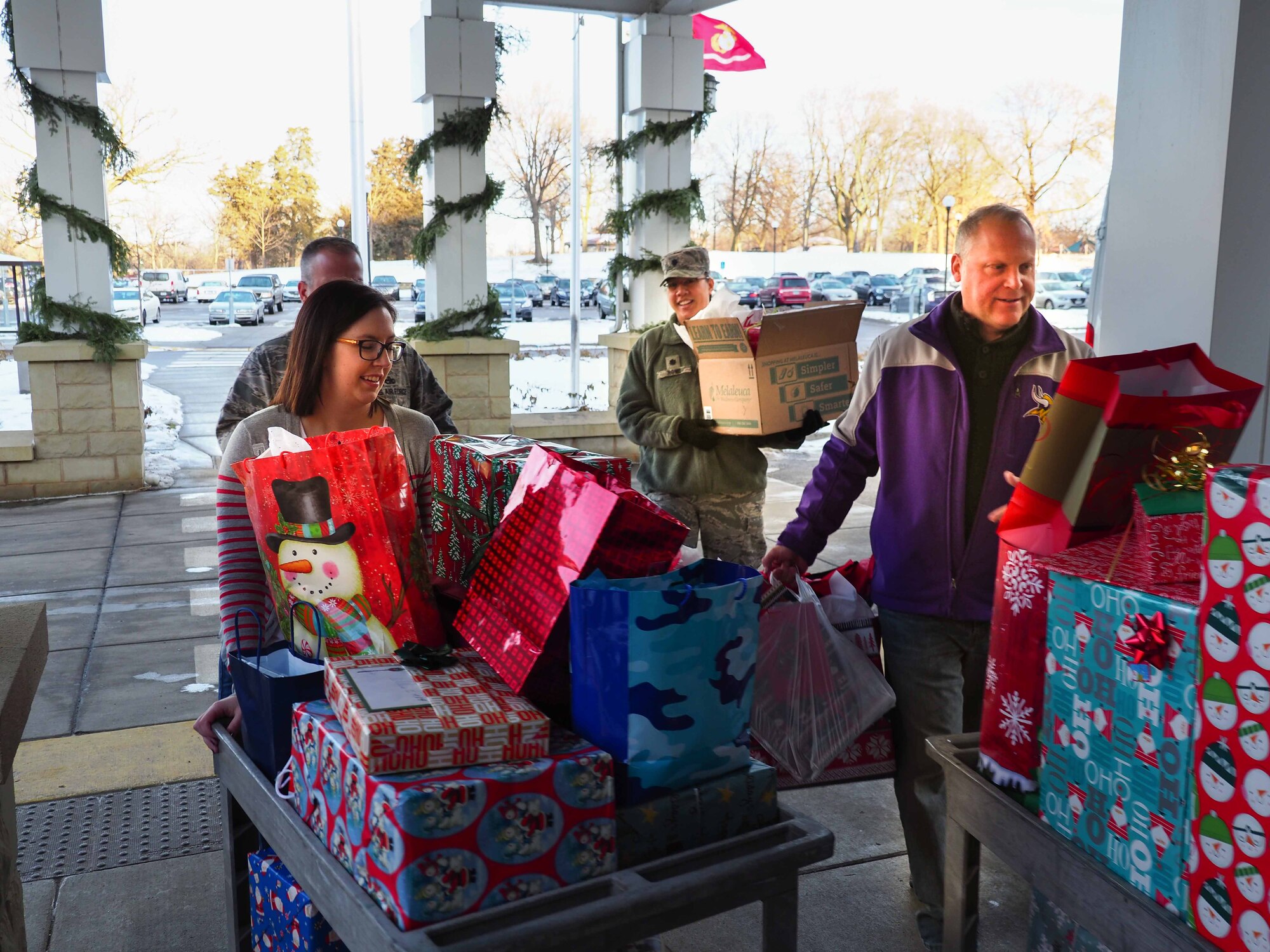 From left, Kate Gorski, Minnesota Veteran's Home, Lt. Col. Karen Rowe and Rick Pelzl, 934 FSS, carry gifts donated by 934 AW Airmen to the Minnesota Veteran's Home Dec. 19. (Air Force Photo/Paul Zadach)