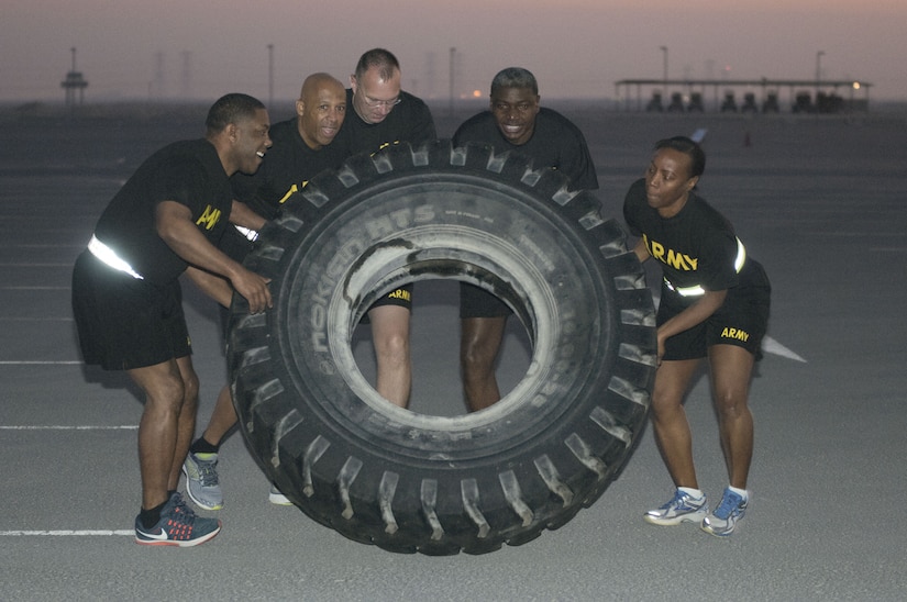 Several Soldiers lifting a large tire.