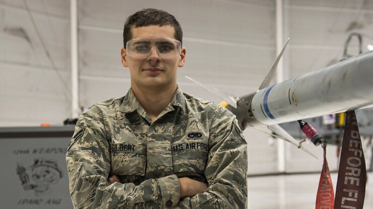 An airman crosses his arms as he poses for a photo.