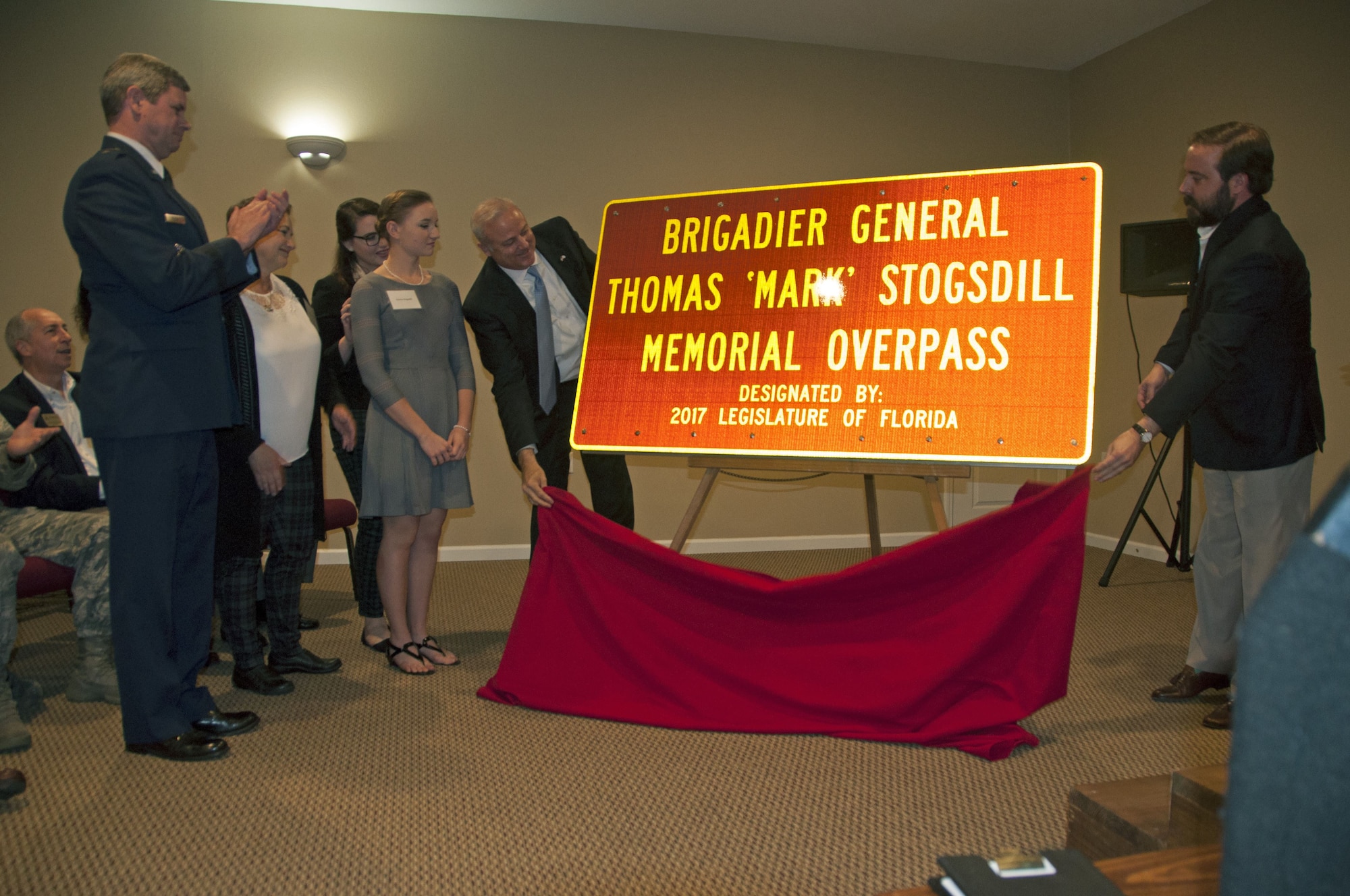 Family members of the late Brig. Gen. Thomas “Mark” Stogsdill witness state officials unveiling a sign dedicating to his memory.