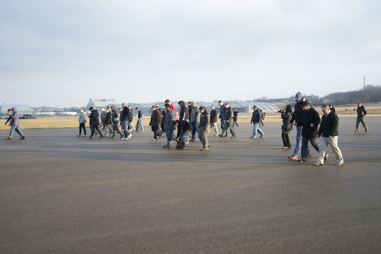 Members of Naval Medical Research Unit-Dayton conduct a foreign-object-damage walk-down Dec. 19, 2017, on the Wright-Patterson Air Force Base, Ohio, Area B flight line in advance of the arrival of a Marine Corps MV-22 Osprey aircraft. The unit was preparing the seldom-used runway near the National Museum of the Air Force for the arrival the plane that was signed over to the unit for medical research. (U.S. Air Force photo by R.J. Oriez)