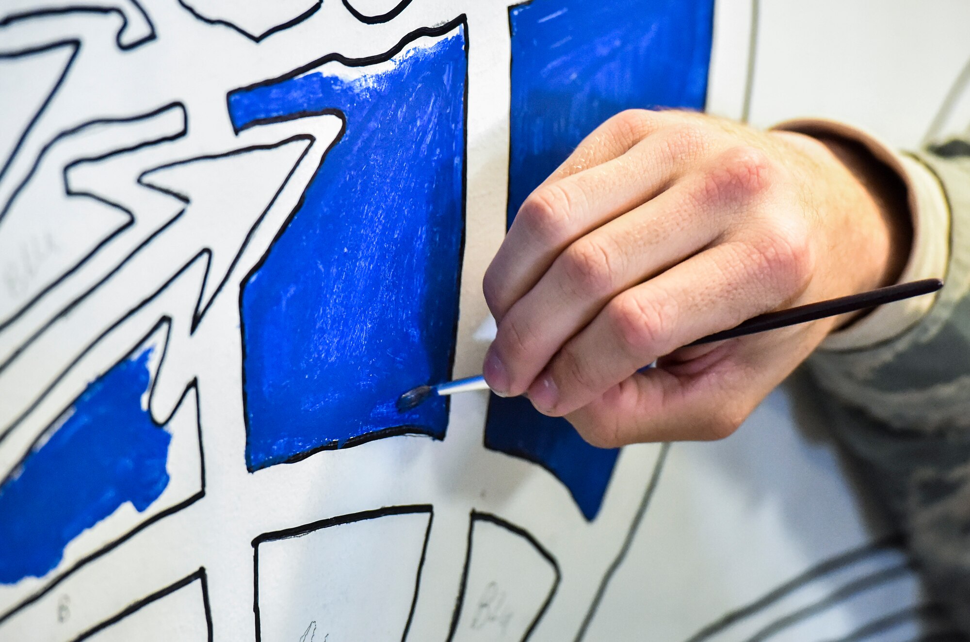 A 628th Logistics Readiness Squadron vehicle operator paints a drawing of a vehicle operator occupational badge at the vehicle operations building on Joint Base Charleston, S.C., Dec. 9, 2017.