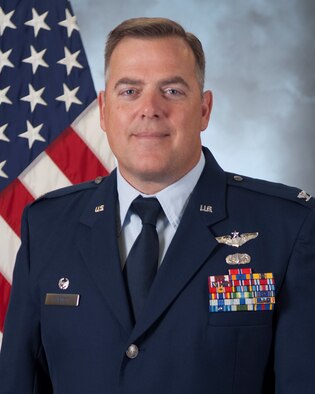 official photo of 505th Training Group commander in service dress with flag in the background.