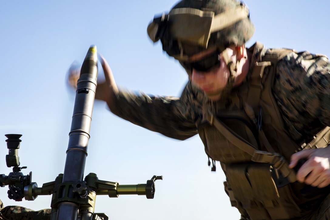 A Marine loads a round into an M224 60 mm mortar system.