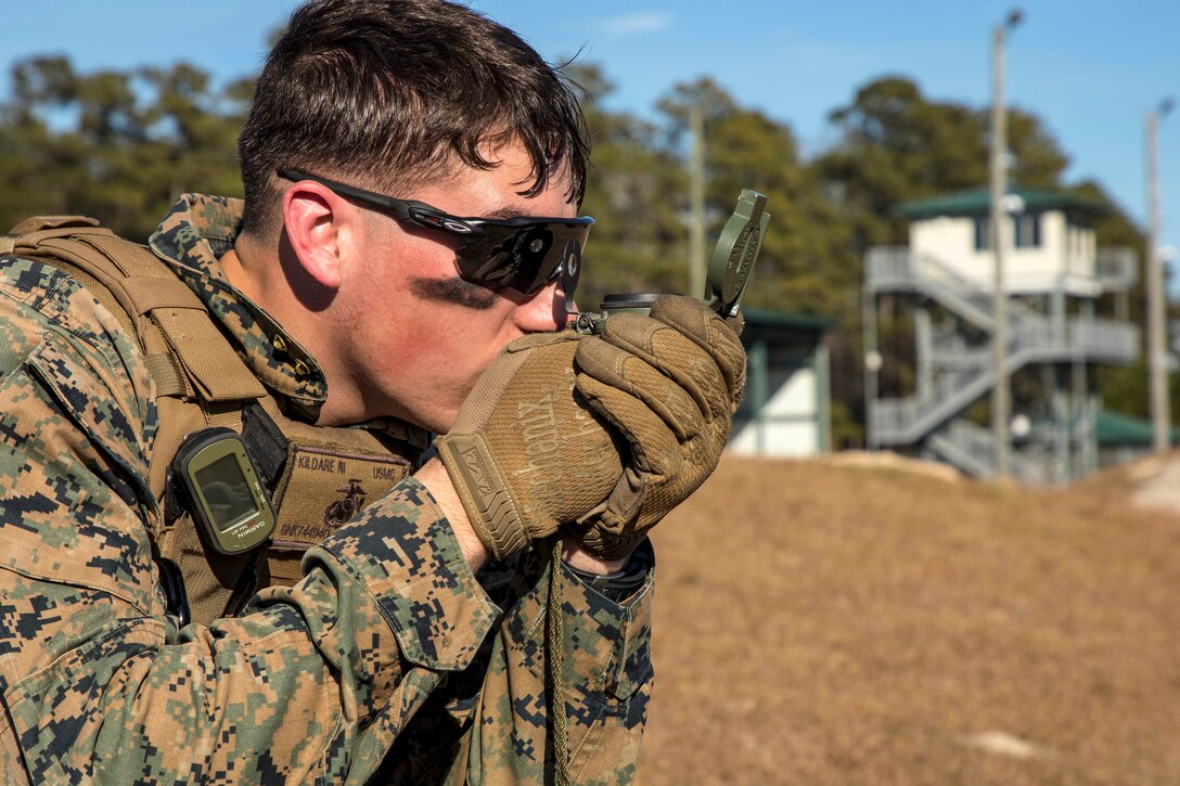 A Marine uses a lensatic compass to determine his lateral firing limits.