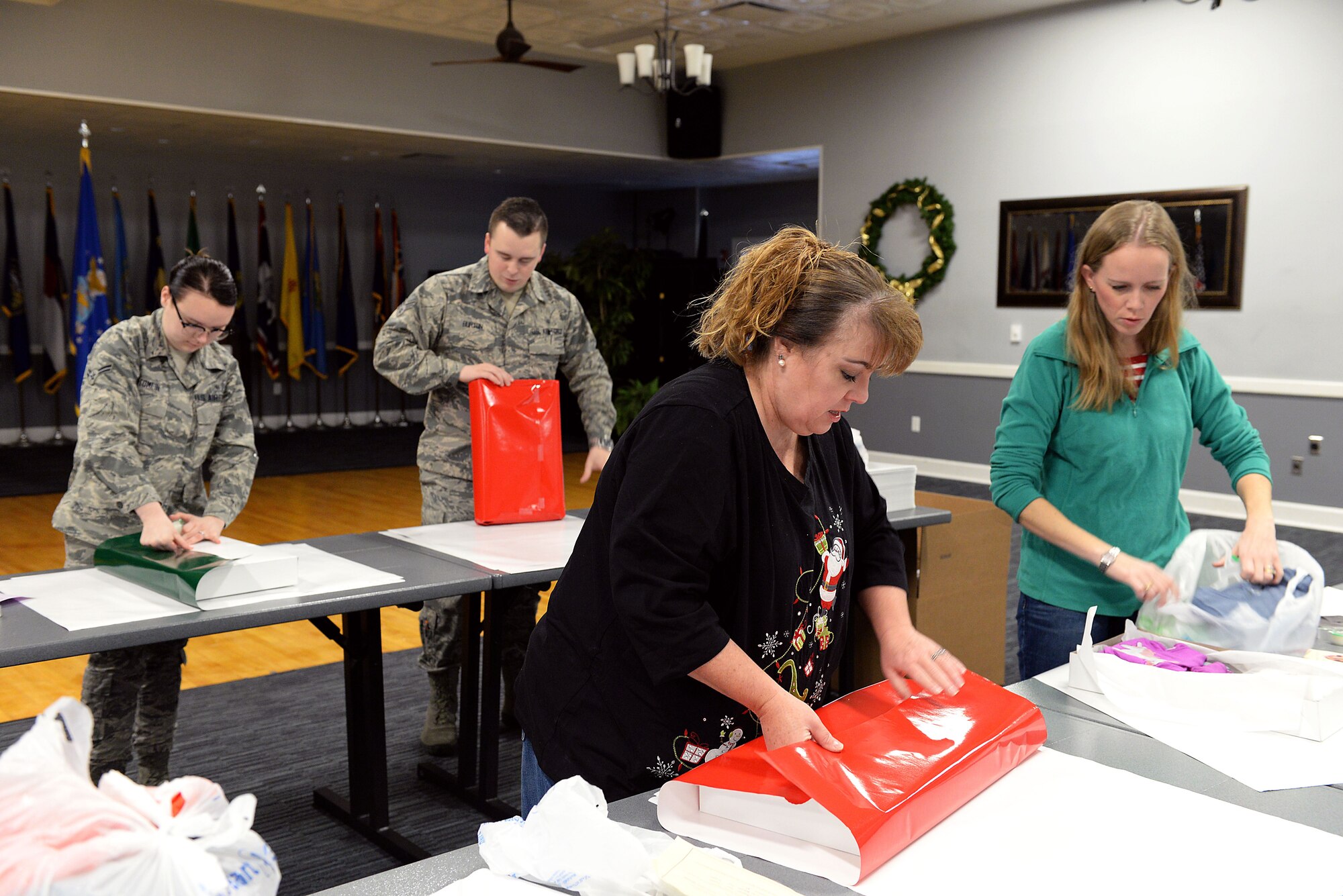Beth Gosney, wife of Col. Douglas Gosney, 14th Flying Training Wing Commander, wraps gifts with Airmen and family members Dec. 14, 2017, on Columbus Air Force Base, Mississippi, during the Happy Fund Shop and Wrap. Over 400 gifts were packed and sent to eight local schools. (U.S. Air Force photo by Airman 1st Class Keith Holcomb)