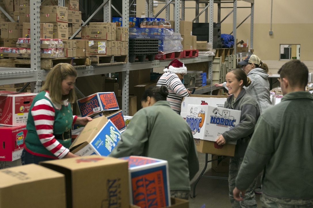 Airmen and volunteers gather boxes in preparation for a cookie drive.