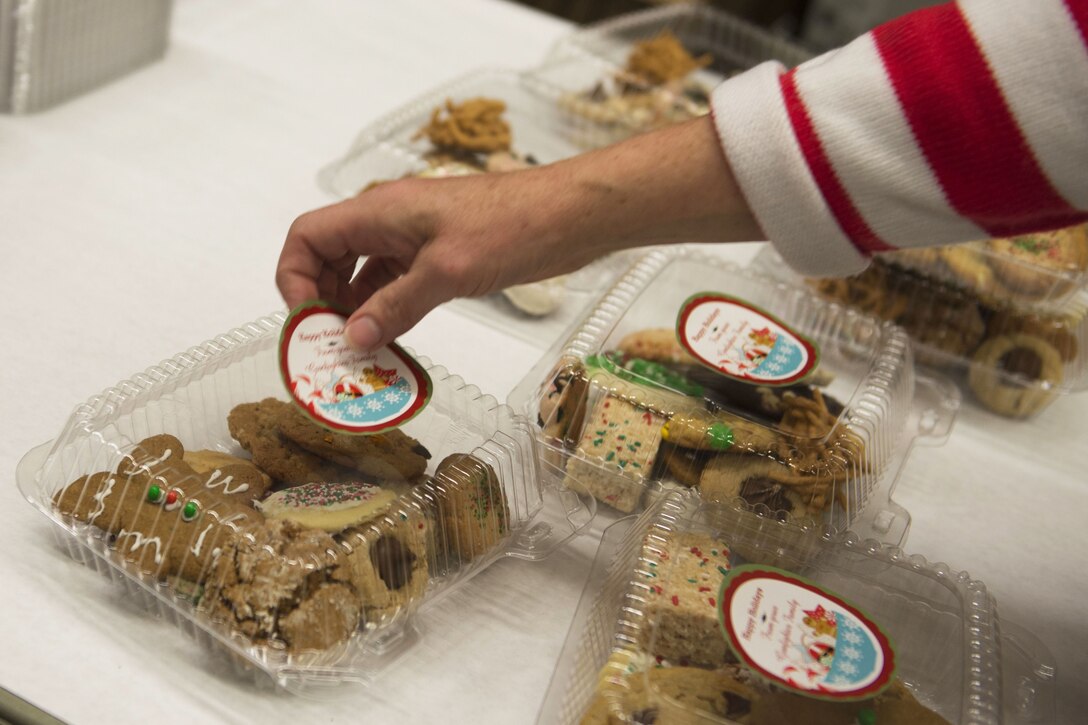 A volunteer applies a holiday sticker to a box of cookies.
