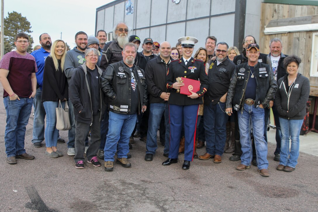 Sergeant Sara McGaffee, a Sioux Falls, S.D., native, poses for a photo with her friends and family after the Marines of Recruiting Sub Station Sioux Falls presented her with the Purple Heart Medal. On Oct. 20th, 2010, while deployed with Combat Logistics Battalion 3, McGaffee’s vehicle was hit by an improvised explosive device while conducting convoy operations in support of Operation Steel Dawn II in the Helmand province of Afghanistan. McGaffee was awarded her Purple Heart, Dec. 16, 2017 in Sioux Falls, S.D., in front of a detail of Marines and her local friends and family.