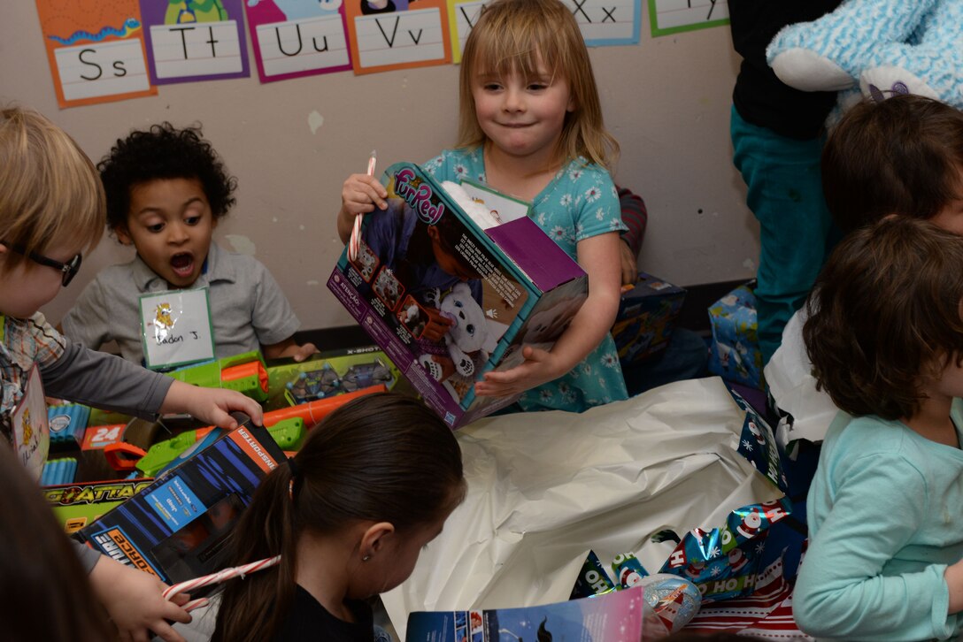 Children tear open presents from Santa inside the Youth & Family Services Child Development Center in Rapid City, S.D., Dec. 19, 2017. This event has been hosted by the 28th Operations Group for 11 years. (U.S. Air Force photo by Airman 1st Class Nicolas Z. Erwin)