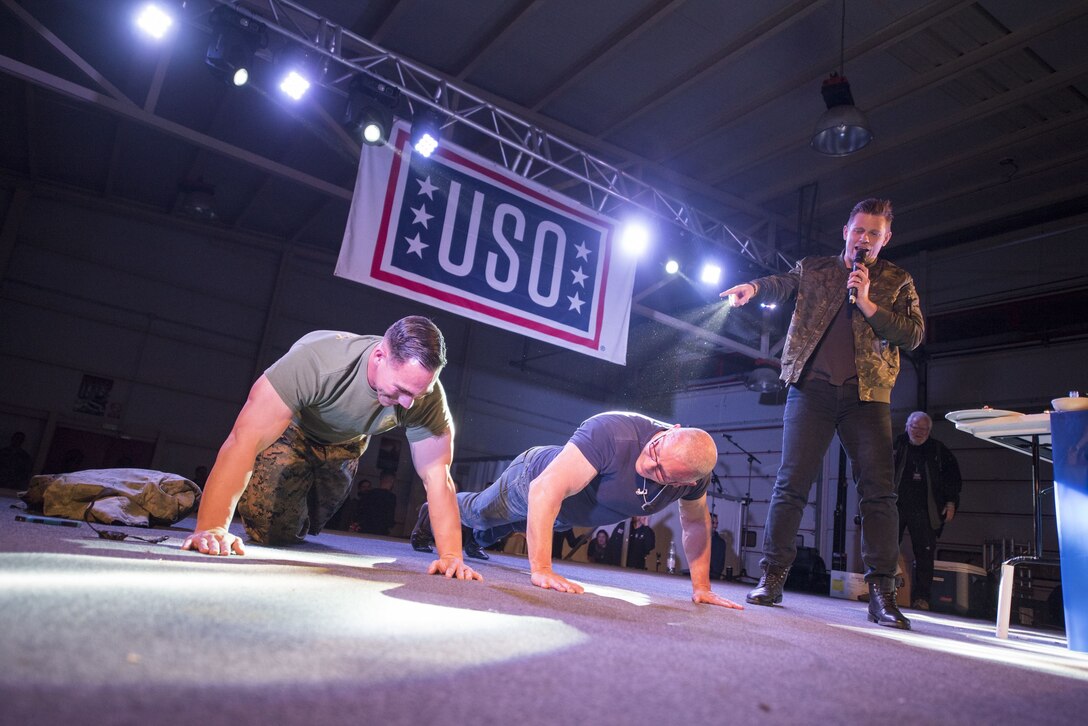 Two men do push ups on stage.