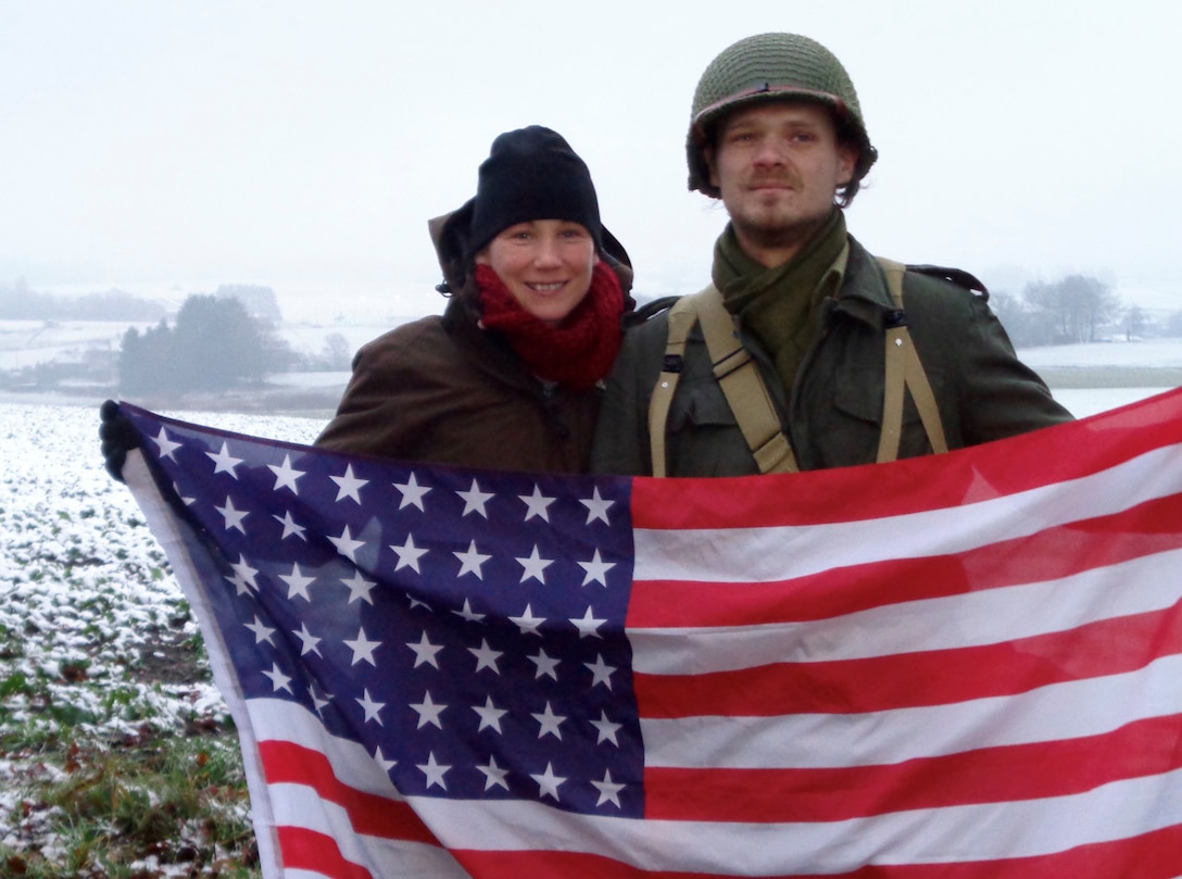 Army Maj. Tracy Yates and a reenactor portraying a U.S. Army soldier who fought in the Battle of the Bulge pose with a period-correct 48-star American flag, Dec. 16 near Bastogne, Belgium. (Photo courtesy DLA Europe & Africa)