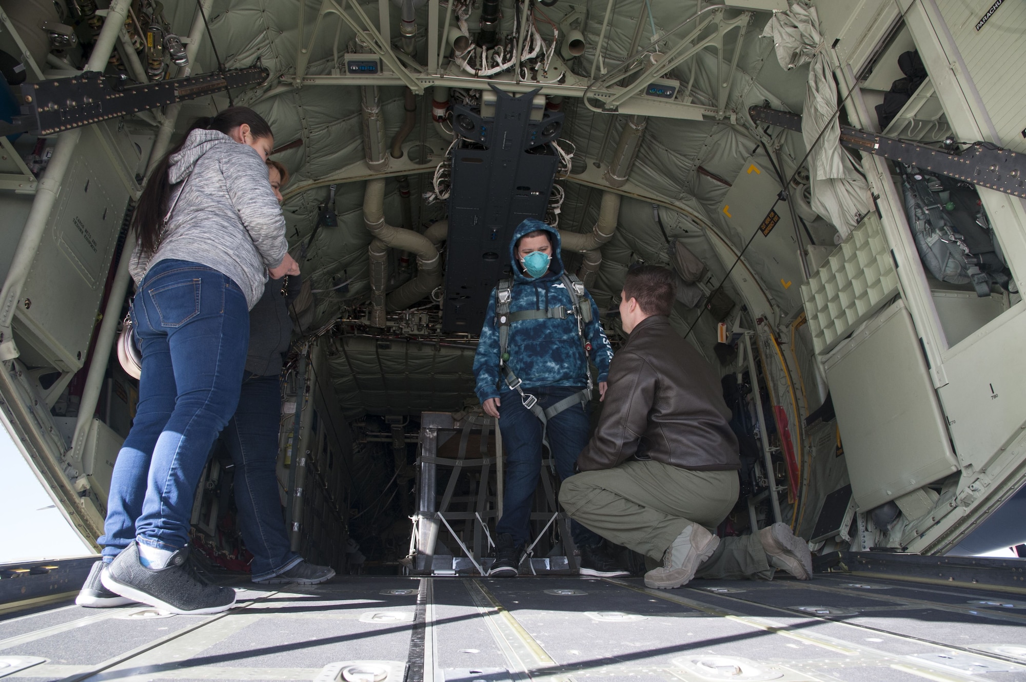 Staff Sgt. Zach Harmon, 58th Special Operations Wing MC-130J aircraft loadmaster, fits a visitor from the Presbyterian and University of New Mexico children's hospital in a parachute aboard a MC-130J, at Kirtland Air Force Base, N.M., Dec. 21.