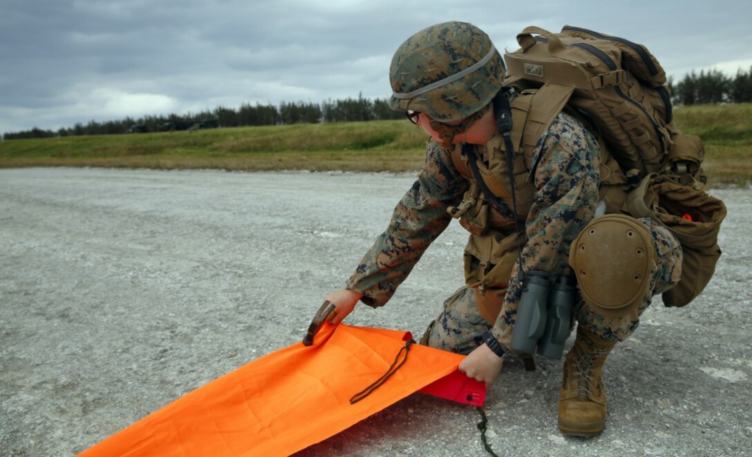 Marine Corps Cpl. Kate Mazzone, a communications technician, secures a panel that will notify an aircraft where to land during Exercise Voodoo Magic on Iejima Island in Okinawa, Japan.