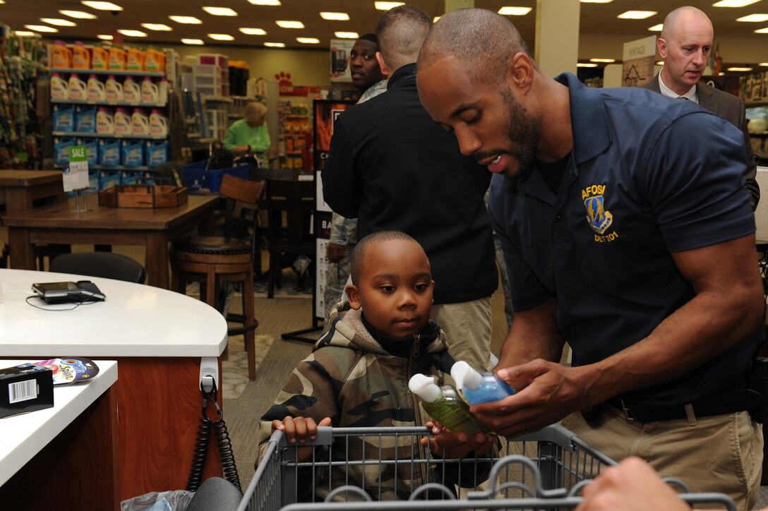 U.S. Air Force Special Agent Brandon Smith, assigned to Air Force Special Investigations at Detachment 201, and mentee Noah Frost, age 6, check-out during the “Shop with a Cop” event at Joint Base Langley-Eustis, Va., Dec. 19, 2017.