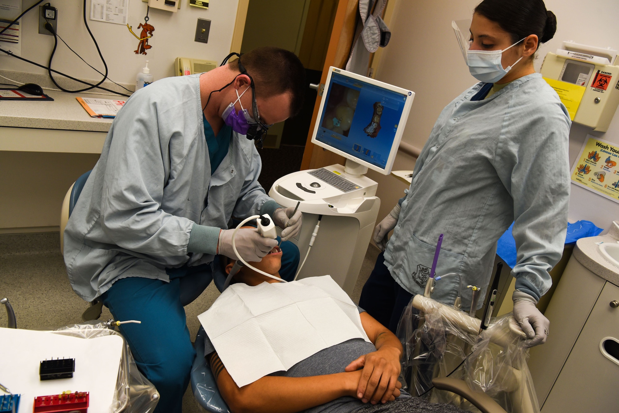 Captain Corey Cook, 90th Medical Group dentist, and Airman 1st Class Amy Demitre, 90th Medical Group dental assistant, scans a patients teeth to make a 3-D photo after removing a silver crown at the dental clinic on F.E. Warren Air Force Base, Wyo., Dec. 19, 2017. The intraoral scanner allows the crown to be designed, made and placed during one appointment, whereas the old technology would take multiple appointments and temporarily result in the patient becoming non-deployable until the new crown was placed. The mission of the U.S. Air Force Dental Corps is to achieve superior oral health and global readiness through safe, effective and patient-centered care. (U.S. Air Force photo by Airman 1st Class Abbigayle Wagner)