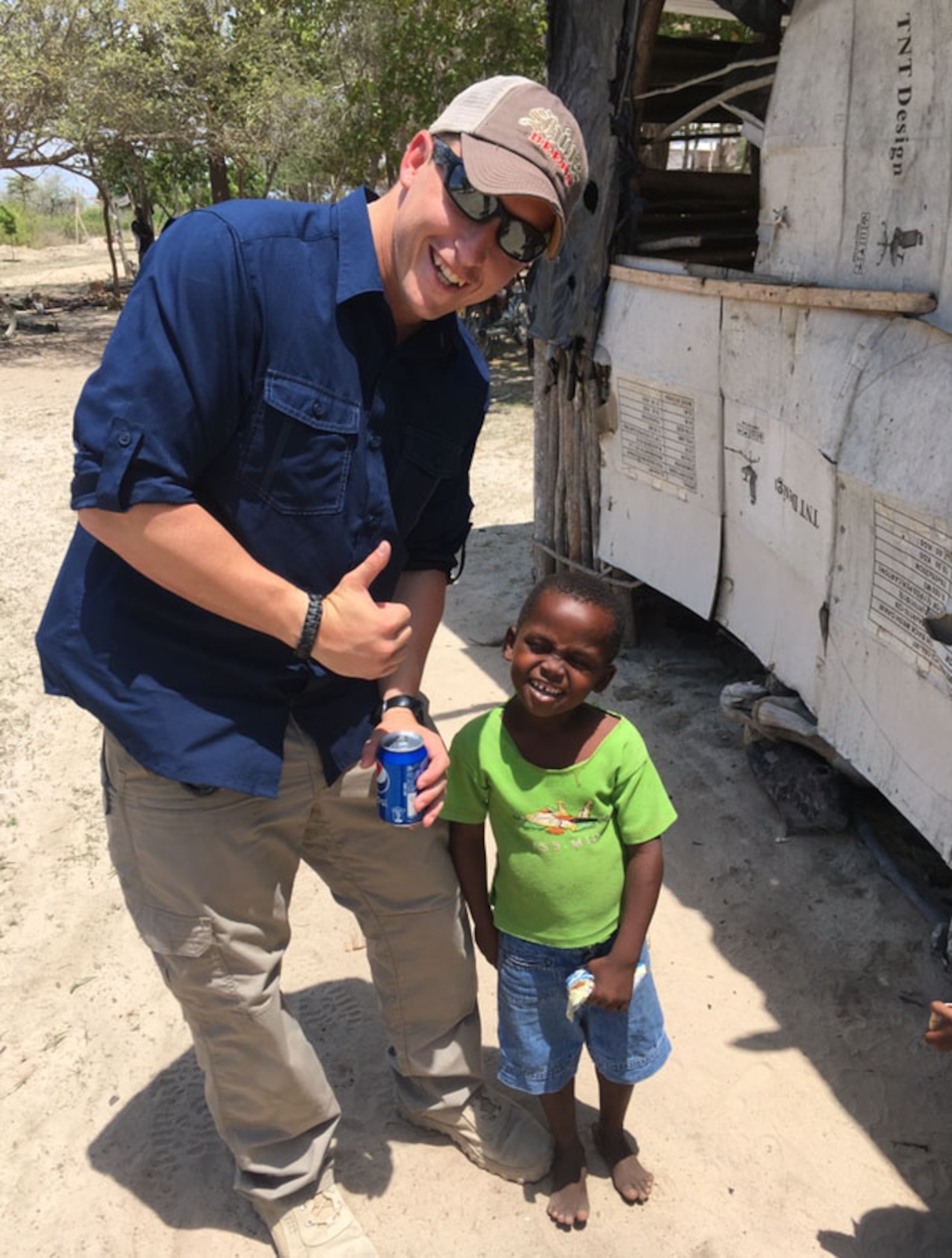 Image of Senior Airman John Dantoni, 366th Security Forces Response Force member, smiles with a child in a Kenyan village. Before this picture was taken, Dantoni taught the child how to open a soda. (Photo courtesy of SrA John Dantoni)