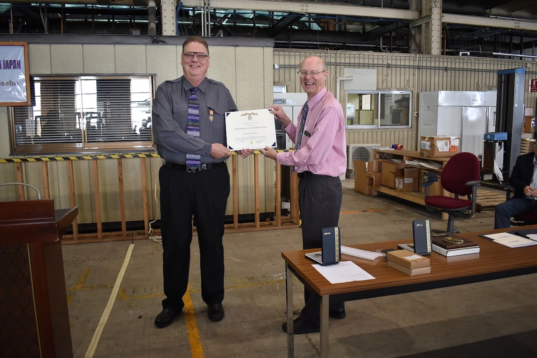 Roy Jewell (right), acting director DLA Distribution Yokosuka Japan presents Joe Pirman with his retirement awards during a town hall on Dec. 4.