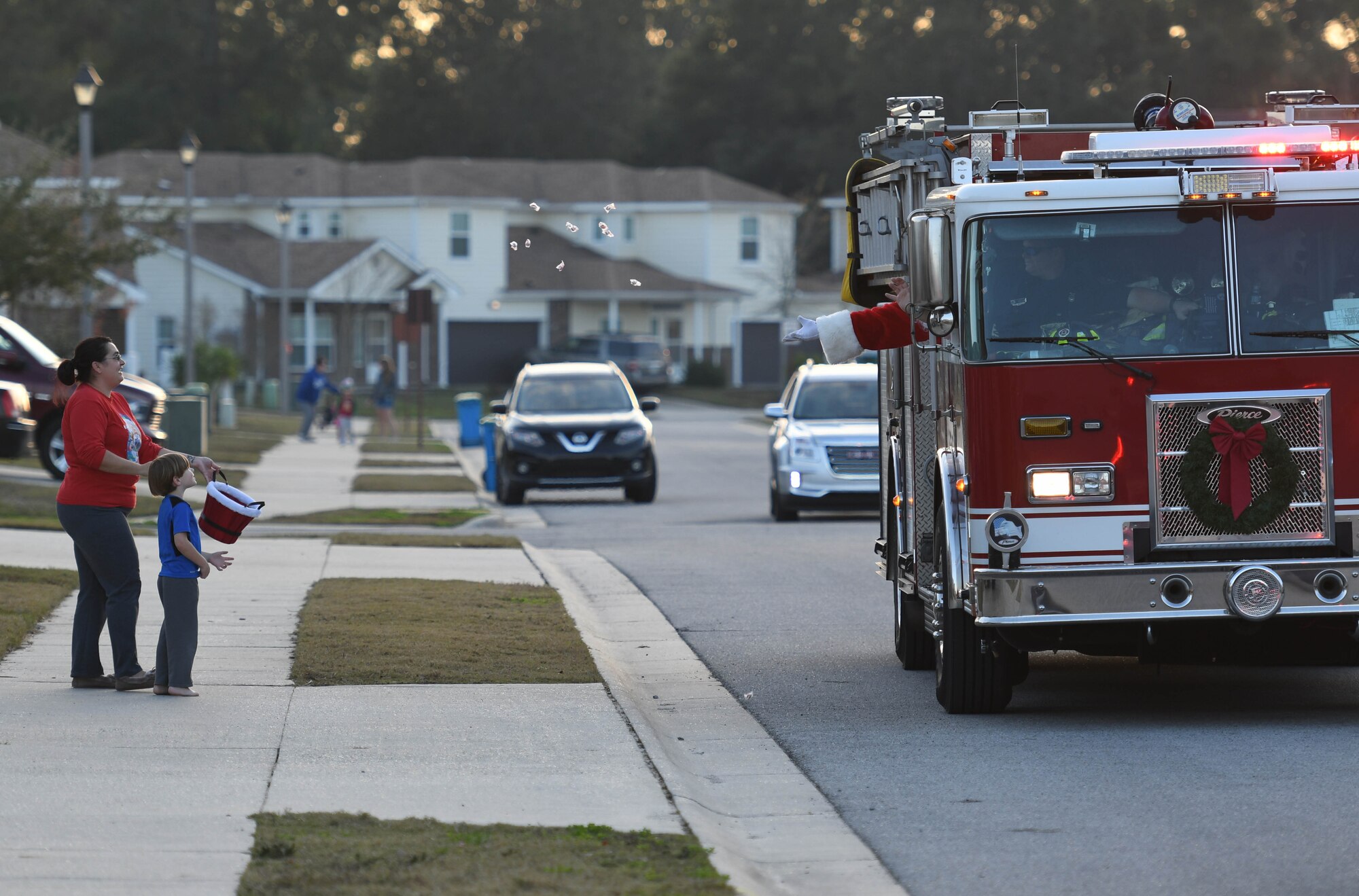 Santa throws candy to Nicole and Luke Stillwagon, family of Master Sgt. Joshua Stillwagon, 334th Training Squadron instructor supervisor, from a fire truck in Bay Ridge housing Dec. 21, 2017, on Keesler Air Force Base, Mississippi. Santa and fire department members drove through each housing area to spread Christmas cheer to Airmen and their families. (U.S. Air Force photo by Kemberly Groue)