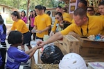 SRIRACHA, Thailand—Aviation Metalsmith 2nd Class Kevin Brown with Patrol Squadron 8, hands a child an items from a U.S. Navy Project Handclasp kit during a community relations event at Map Yang Ra Hong primary school in Chantaburi, Dec. 16. Patrol Squadron 8 is a U.S. Navy land-based patrol squadron stationed at Naval Air Station Jacksonville, Fla., and deployed to Okinawa, Japan. Military Sealift Command fleet replenishment oiler USNS Pecos (T-AO 197) recently transported two tons of U.S. Navy Project Handclasp humanitarian items from Singapore to Thailand that supported four community relations events at local organizations here.